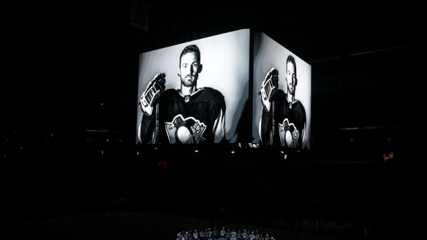 Oct 30, 2023; Pittsburgh, Pennsylvania, USA; Members of the Anaheim Ducks and the Pittsburgh Penguins stand at center ice for a moment of silence at the PPG Paints Arena to honor former Penguin forward Adam Johnson (on scoreboard) who was tragically killed in a hockey related accident in Europe.